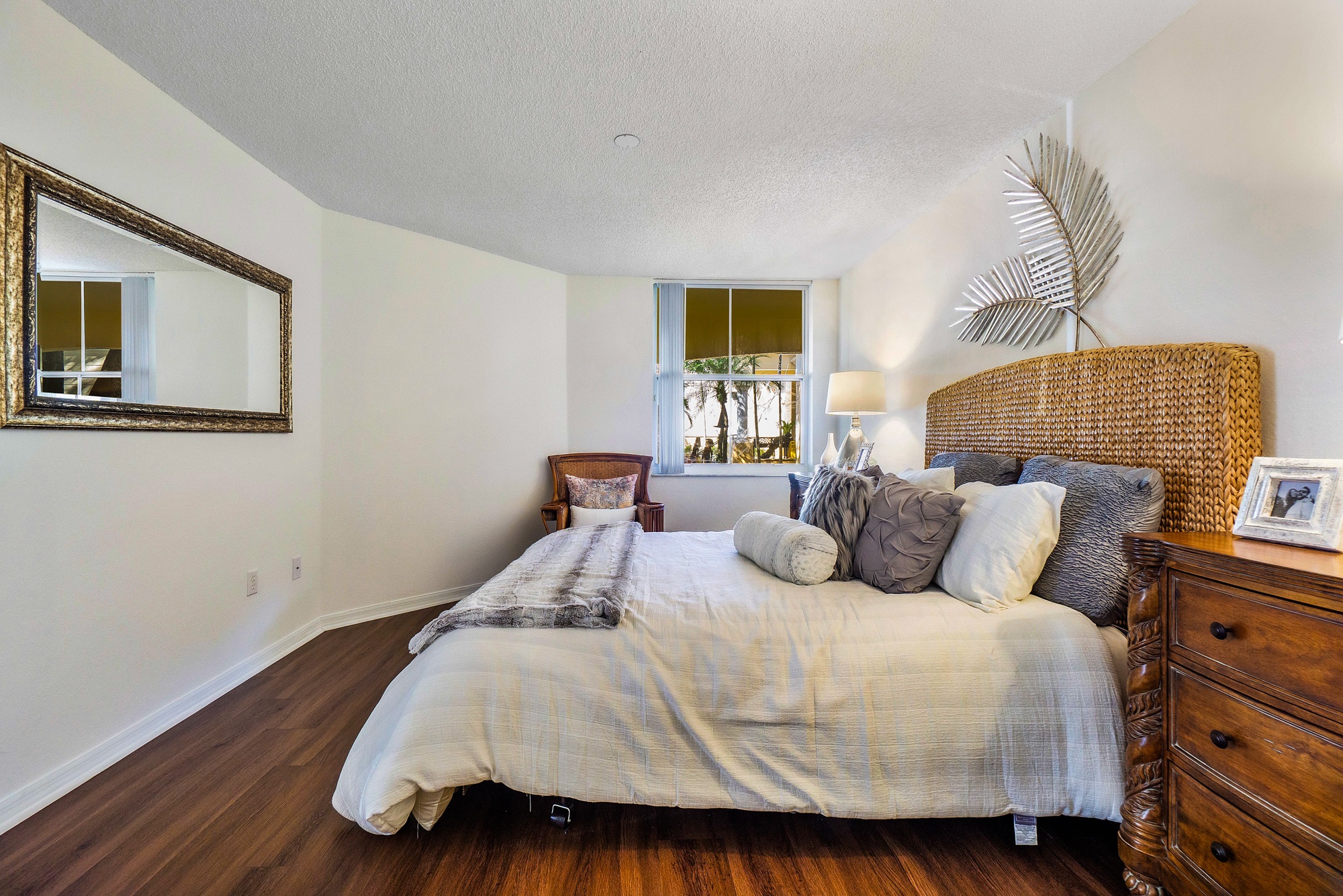 A bedroom with a large bed and a wicker headboard.